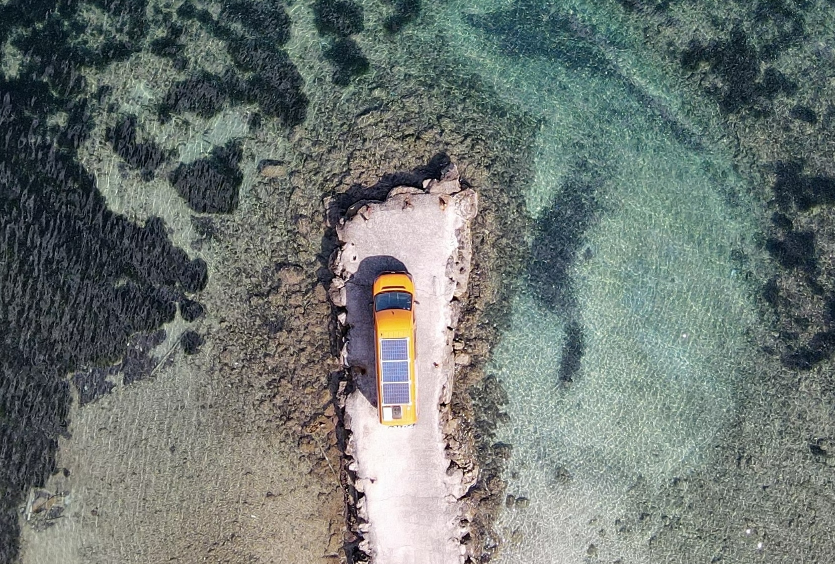 Campervan parked by crystal clear Cyprus waters with mountains in background